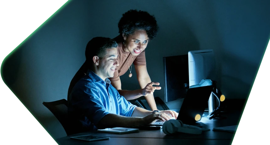 Two people looking at a computer screen in the dark